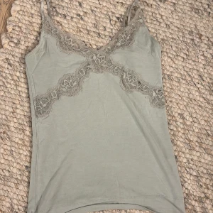 Mintgrön  linnetopp från By Malene Birger - Snygg mintgrön  linnetopp från By Malene Birger med spetsdetaljer vid halsringningen. Perfekt för en stilren look. Toppen har smala axelband och en mjuk känsla.