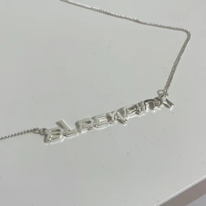 Silverfärgat BLACKPINK halsband - Snyggt silverfärgat halsband med texten 'BLACKPINK'. Perfekt för fans av gruppen eller som ett stilrent smycke till vardags. Kedjan är tunn och elegant, vilket gör det lätt att matcha med andra accessoarer. Helt nytt och oanvänt!