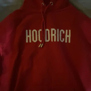 Hoodrich dress - Säljer en snygg röd hoodie från HoodrichHelt nytt skick!. Den har en klassisk design med en stor logga på bröstet och en mindre på ärmen. Perfekt för en casual look eller att mysa i hemma. Den är i bra skick och superbekväm! 