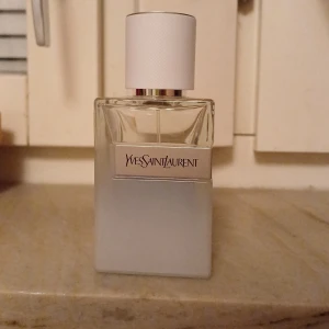 Parfym från Yves Saint Laurent - Säljer en elegant parfym från Yves Saint Laurent. Flaskan är stilren och fyrkantig med en frostad glasdesign som ger en lyxig känsla. Den har en vit kork och märket är tydligt tryckt på framsidan. Perfekt för både vardag och speciella tillfällen! Sommar parfym och jätte fresh lukt!
