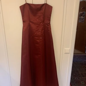 Vinröd balklänning ⋆ ˚｡⋆౨ৎ˚ - Jättevacker 90s vinröd bal/galaklänning! Köpt på sellpy och aldrig använd, endast testad. Vackra broderade blommor och en fin knytning i ryggen. Har korsettliknande stöd vid bysten. Perfekt till student eller skolbal! Skriv gärna om du har frågor <3