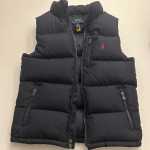 Polo Ralph Lauren RIPSTOP DOWN GILET - Säljer sonens Polo Ralph Lauren väst! Den är Max använd 3 gånger och är i ny skick. Storlek 150 och passar 10-12 år. Nypris 2699kr  Mitt pris 1500kr