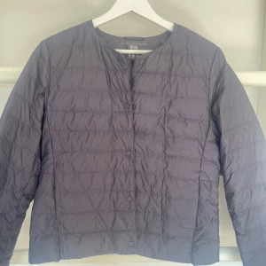 Grå quiltad jacka från Uniqlo - Säljer en stilren och lätt gråblå quiltad jacka från Uniqlo. Perfekt för höst och vår med sin lätta design och knäppning fram. Jackan har långa ärmar och en normal passform, vilket gör den superbekväm för vardagsbruk. Knappast använd nypris 600kr
