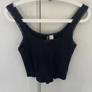 Linne - Svart spetslinne med en söt rosett, lite croppad