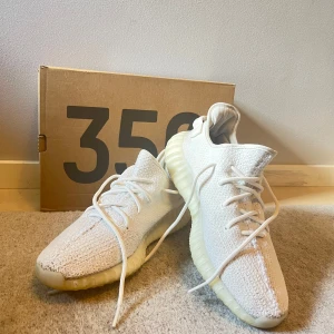 Adidas Yeezy Boost 350 V2 i ljusgrå - Säljer ett par Adidas Yeezy Boost 350 V2 i en snygg ljusgrå färg. Skorna har en stickad ovandel och en bekväm Boost-sula. De är i bra skick och kommer med originalförpackning. Perfekta för både vardag och fest!