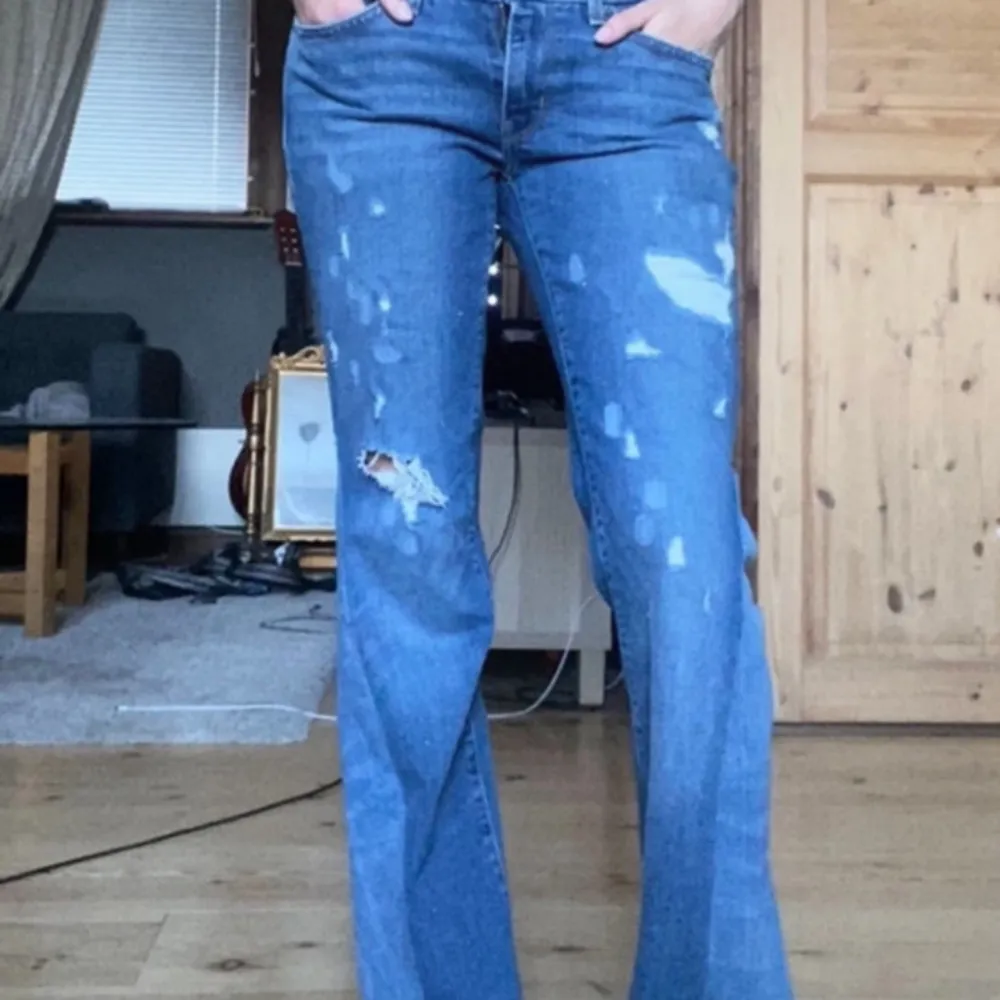 Sjukt snygga Levis jeans med slitningar och utsydda detaljer på sidorna. Midjemåttet tvärsöver är 39 cm och innerbenslängden är cirka 80 cm. Jag på bilden är 166 cm och skulle säga att jeansen passar någon med storlek S. Jeans & Byxor.