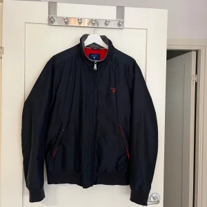 GANT - The New Hampshire Jacket - Riktigt sjysst jacka från GANT till höst/vår/sommar. Jackan är i mycket fint skick. Nypris 3000kr.  Storlek är M, men passar även för de som normalt har storlek S.  The New Hampshire Jacket. Färg: Dark navy blue.