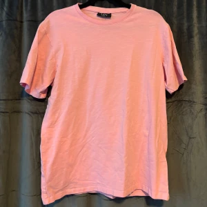 Rosa t-shirt från Smog - Säljer en snygg rosa t-shirt från Smog/New Yorker i regular fit. Perfekt för sommardagar eller som ett lager under en tjockare tröja. T-shirten är gjord i ett mjukt material som känns skönt mot huden. Använd endast 1 gång.