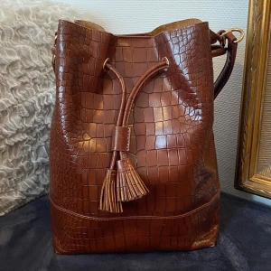 Läderväska - Äkta läderväska från Hobbs London. Rödbrun i croco-mönster. Använd fåtal gånger. Inga defekter. Medföljer tillhörande pouch och axelrem. Pris kan diskuteras. Hör av dig om du har frågor💓