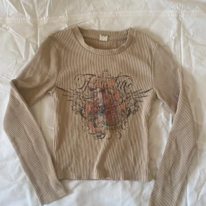 långärmad topp med tryck - en långärmad topp med tryck från urban outfitters, har en litet hål vid ena axeln se bild 