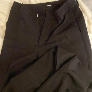 Svarta kostymbyxor från BikBok - Säljer ett par stilrena svarta kostymbyxor från BikBok. De är perfekta för både jobb och fest och har en klassisk design med dragkedja och knappar. Byxorna är i ett bekvämt material som ger en snygg passform.