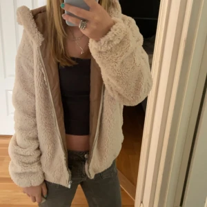 Beige teddyjacka med huva - Supermysig beige teddyjacka med huva, perfekt för kyliga dagar. Jackan har en dragkedja framtill och är långärmad. Den är i en loose passform vilket gör den extra bekväm och skön att ha på sig. Perfekt för höst och vinter!❤️☺️😇
