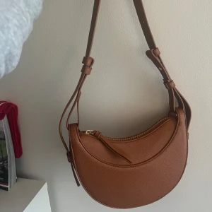 Axelrem/sadelväska - Väldigt fin brun väska med gulddetaljer som är köpt på Amazon för några månader sen. Väskan har inga defekter och har ändast använt den fåtal gånger.