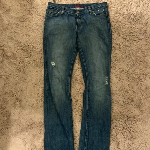 Blå jeans från Miss Sixty - Snygga blå jeans från Miss Sixty med slitna detaljer på framsidan. De har en klassisk femficksdesign och en knappgylf. Perfekta för en avslappnad stil.