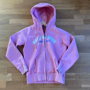 Rosa hoodie från Race Marine - Säljer en rosa hoodie från Race Marine med dragkedja och kängurufickor. Den har ett tryck på bröstet och ribbade muddar vid ärmsluten. Perfekt för en avslappnad stil. Har några hål vid ärmarna och ett vid trycket men inget man märker eller förstör☺️