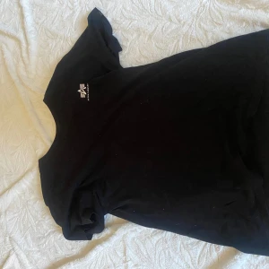 Svart t-shirt med tryck - Säljer en svart t-shirt med ett litet tryck på bröstet. T-shirten är kortärmad och har en klassisk passform. Perfekt för en avslappnad stil.