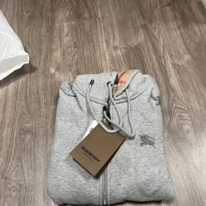 Grå hoodie  Burberry - Säljer en helt ny burberry hoodie/kofta! De är i påset och tagg är med! Jag tycker riktigt inte om det och passar inte min stil därför jag säljer den! M men passar S