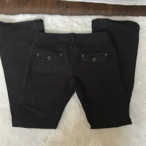 Snygga svarta bootcut byxor med dekorativa knappar på fickorna. I storlek 34.
