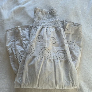 Beige kjol med broderade detaljer - Charmig beige kjol med vackra broderade cirkelmönster och elastisk midja. Tillverkad i Italien, perfekt för en bohemisk look. Kjolen har en luftig och bekväm passform med volangdetaljer som ger extra stil.