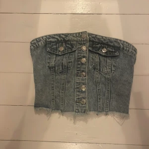 Jeans korsett från Shein - Säljer en cool jeans korsett från Shein med knappar framtill och fransig nederkant. Den har en elastisk rygg för bättre passform och dekorativa fickor framtill. Perfekt för en trendig look!