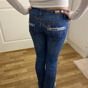 Blå jeans med detaljer från Even  - Snygga blå jeans från Even med unika broderade detaljer och nitar på bakfickorna. Jeansen har en knappgylf. Midjemåttet rakt över är 35 och innerbenslängden är 84,5. Helt ny köpta från Vinted men var tyvärr för små för mig❤️ ( min kompis på bilden )