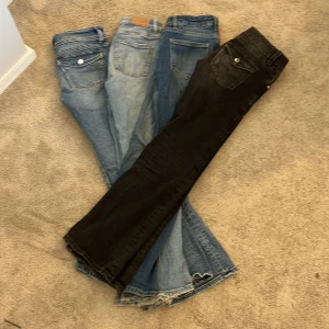 Jeans från Gina Tricot i olika färger - Säljer fyra par jeans från Gina Tricot. Ett par svarta och tre par blå jeans med klassisk design. Perfekta för en avslappnad stil. De har fickor och knappdetaljer. Ett par för 200 och alla för 750