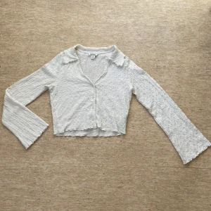 Vit flared långärmad topp - Säljer en vit långärmad topp från Monki med flared ärmar och vita knappar framtill. Toppen har en lätt croppad passform och en mjuk krage.