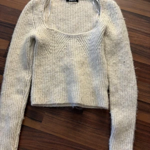 Beige stickad tröja från Gina Tricot - Säljer en beige stickad tröja från Gina Tricot. Tröjan är croppad med långa ärmar och har en ribbad struktur. Perfekt för kyligare dagar.