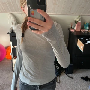 Grå långärmad topp från Cubus - Säljer en stilren grå långärmad topp från märket Cubus. Toppen är i en mjuk och skön bomullsmix, idealisk för vardagsbruk. Passar till allt och en väldigt enkel tröja. Andvänd fåtal gånger. Pris går att diskutera!💕