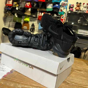 Svarta Nike Air Vapormax - Snygga svarta Nike Air Vapormax med en modern design och bekväm passform. Skorna har en stickad ovandel och en unik sula med synliga luftkuddar för extra dämpning. Perfekta för både stil och komfort.