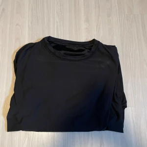 Svart tränings T-Shirt från NewBody - Säljer en svart t-shirt med korta ärmar. Perfekt för träning eller vardagsbruk. Materialet verkar vara syntetiskt och andas bra, vilket gör den idealisk för aktiva dagar.