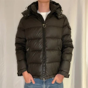 Svart dunjacka/vinterjacka  från Moncler M/L - Säljer en snygg svart vinterjacka från Moncler. Jackan har en quiltad design med dragkedja och huva. Perfekt för kyliga dagar och ger en stilren look. Passar bra till jeans och sneakers. Hör av er om ni har frågor gällande jackan storlek 4 på moncler!
