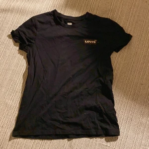 Svart t-shirt från Levi's - Säljer en svart t-shirt från Levi's med ett coolt leopardmönstrat tryck på bröstet. T-shirten är kortärmad och tillverkad i bomull, perfekt för en avslappnad stil. Passar bra till jeans eller shorts för en casual look. Knappt andvänd