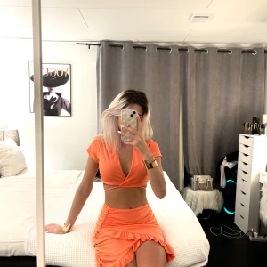 Orange croppad klänning  - Säljer en snygg orange croppad Kläning  med korta ärmar och djup v-ringning. Perfekt för sommarens varma dagar. Matcha med en kjol eller jeans för en cool look.