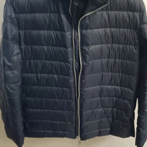 Marinblå dunjacka från Matinique - Snygg svart dunjacka från Matinique i storlek M. Jackan har en dragkedja framtill och är quiltad för extra värme. Perfekt för kyligare dagar med sin stilrena design och bekväma passform.