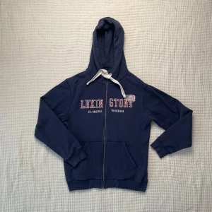 Blå ziphoodie från Lexington - Snygg blå hoodie från Lexington med dragkedja och vit snörning i huvan. Storlek L men är liten i storleken, så om du har M passar den dig. 