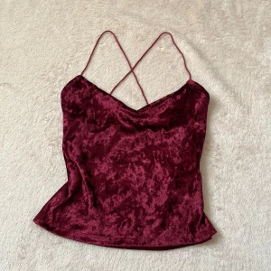 Vinröd sammetstopp - Snygg vinröd sammetstopp med smala axelband och v-ringning. Toppen är croppad och har en mjuk, lyxig känsla. Helt oanvänd (men utan prislapp), strl XS