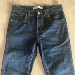 Mörkblå jeans från Levi's - Snygga mörkblå jeans från Levi's med klassisk femficksdesign och kontrastsömmar. Perfekt för en stilren look. Märkeslappen syns tydligt på baksidan.