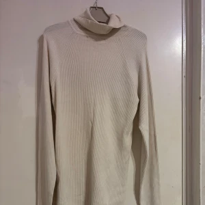 Vit ribbad polotröja från Gina Tricot - Säljer en stilren vit ribbad polotröja från Gina Tricot. Är i storlek XL men sitter som M/L. Tröjan har en hög krage och långa ärmar, perfekt för kyligare dagar. Den är både bekväm och trendig, ett måste i garderoben! 