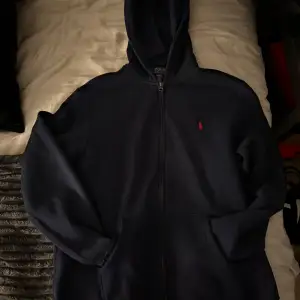Säljer en snygg mörkblå hoodie från Polo Ralph Lauren med dragkedja och det klassiska röda broderade logotypen på bröstet. Perfekt för en avslappnad stil. Kom i dm om minsta lilla fundering! Size L men sitter som S då det är en barnstorlek.
