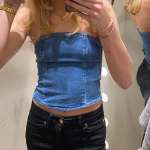 Jeans tubtopp - Säljer en snygg jeans tubtopp i blått. Toppen har en dragkedja på baksidan för enkel på- och avtagning. Ända defekten är att ett band som ska fästa i en knapp nästan är sönder (som man ser på bild 2) men det är inget man tänker på, då den sitter på insidan!💙💙köpt för 400 kr