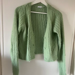 Grön kofta från Bubbleroom  - Säljer en mysig grön kofta från Bubbleroom. Den har en fluffig textur och stängs med knappar framtill. 