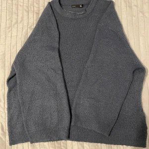 Blå stickad tröja från 157 - Säljer en mysig blå stickad tröja från 157. Tröjan har en klassisk rund hals och långa ärmar, perfekt för kyligare dagar. Den är i storlek L och passar bra för en avslappnad stil.