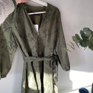 Grön klänning - Grön oanvänd klänning från Zara, superfint mönster i broderi, knytning i midjan och knappar framtill❤️ prislapp kvar💕