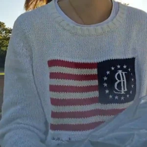 Vit stickad tröja från Bondelid - Säljer en vit stickad tröja från Bondelid med ett amerikanskt flaggmönster på framsidan. Tröjan har långa ärmar och en rund halsringning. 