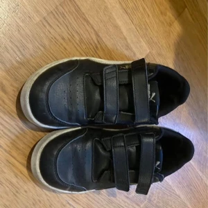 Svarta sneakers med kardborreband Puma - Snygga svarta sneakers från Puma med praktiska kardborreband för enkel på- och avtagning. .