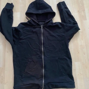 Svart hoodie med dragkedja - Säljer en klassisk svart hoodie med dragkedja och huva. Tröjan har långa ärmar och en bekväm passform. Perfekt för en avslappnad stil.