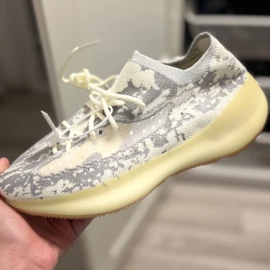 Adidas Yeezy i grå och beige - Snygga Adidas Yeezy sneakers i en cool grå och beige färgkombination. Skorna har ett unikt mönster och en bekväm, tjock sula i gult. Perfekta för dig som vill ha en stilren och modern look. Aldrig använd och finns ej kvitto!