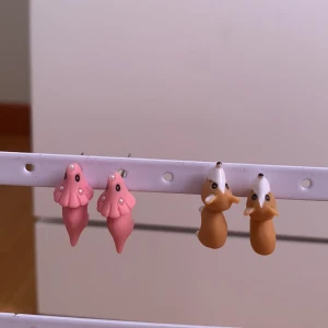 Söta örhängen med djurmotiv - Säljer örhängen i form av små djur, ett par rosa dinosaurier och ett par bruna hundar. Hunden är aldrig använd men dinosaurierna är använd nån enstaka gång. Dem är från temu men i bra skick och därför säljer jag dem billigt. De kostar 10 kr styck men pris kan diskuteras💗