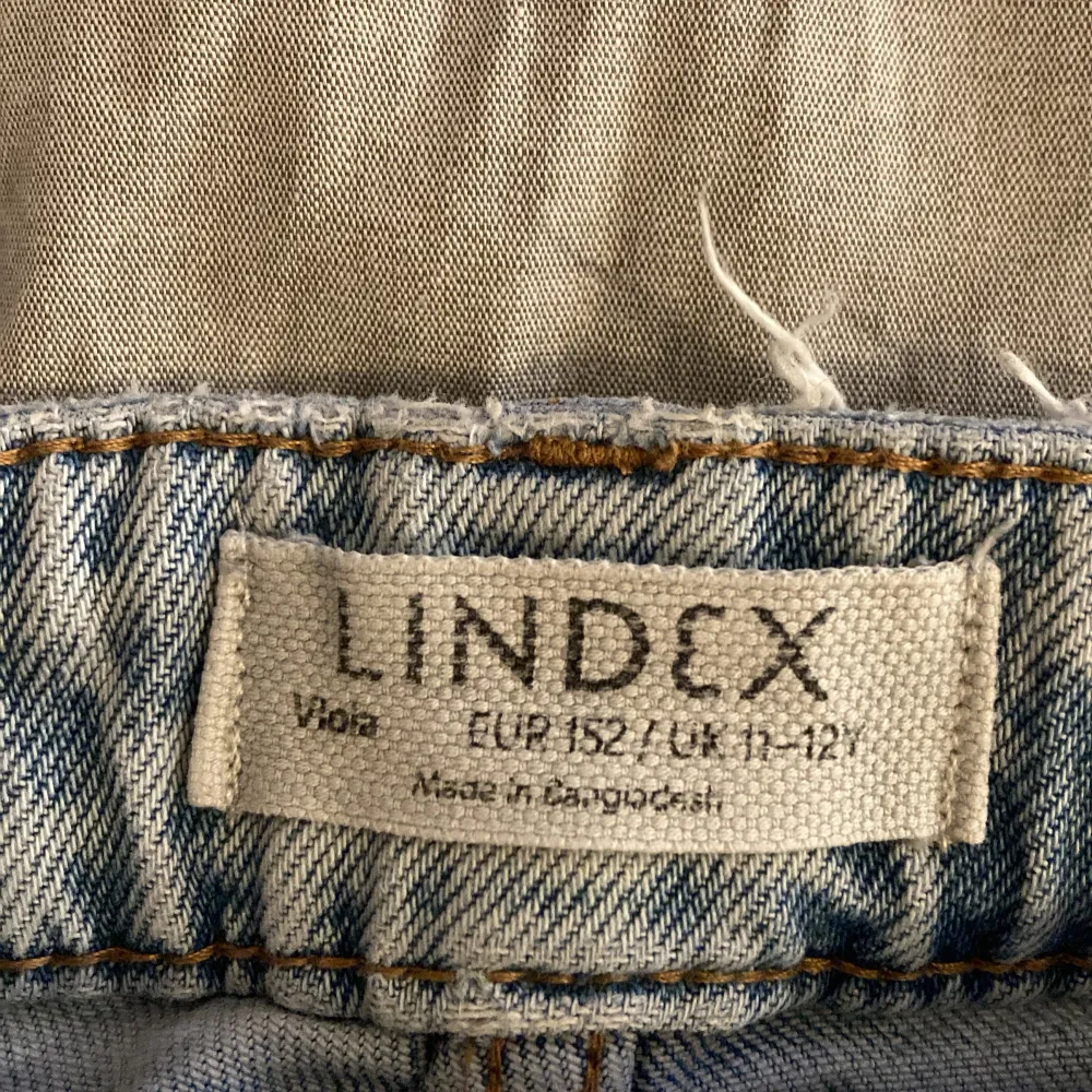 Säljer ett par ljusblå jeansbyxor från Lindex. De har en avslappnad passform med vida ben och är högmidjade. Perfekta för en casual look. Det finns en liten reva och en fläck som inte går bort i tvätten på ena benet. Är i bra skick storlek 152. Kontakta för mer 🤍. Farkut & Housut.